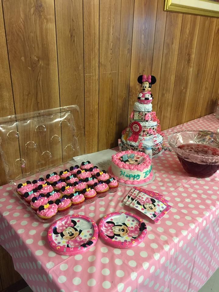 Minnie Mouse-themed birthday party: cupcakes, cake, diaper cake, pink polka dot tablecloth, and decorations.