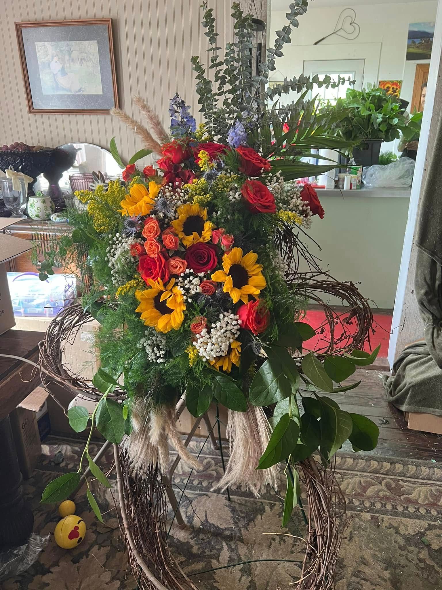 Floral arrangement with sunflowers, roses, and greenery.