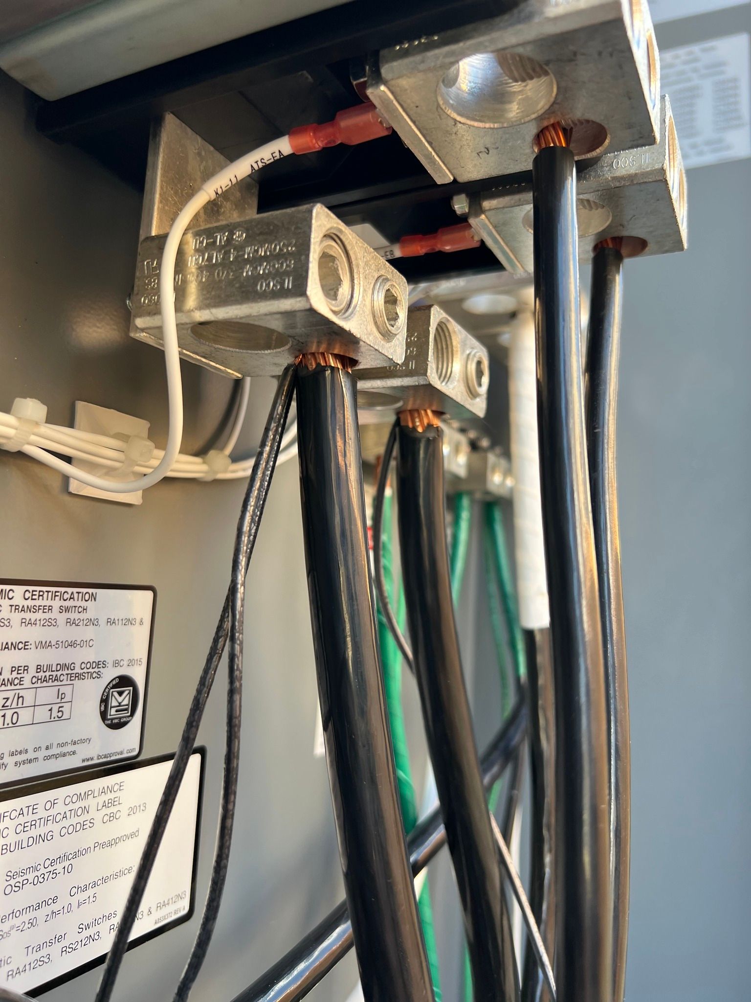 Electrical wires connected to a metal terminal block in a gray electrical panel.