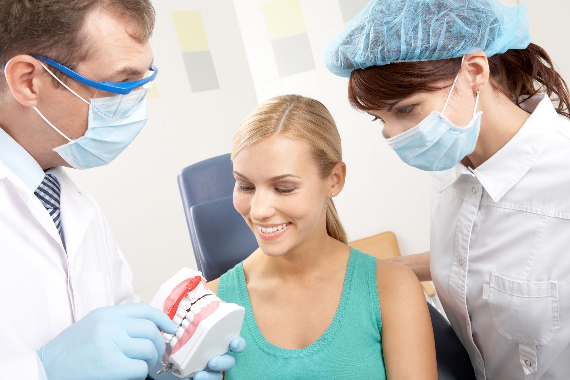 A dentist showing a woman how to brush her teeth.