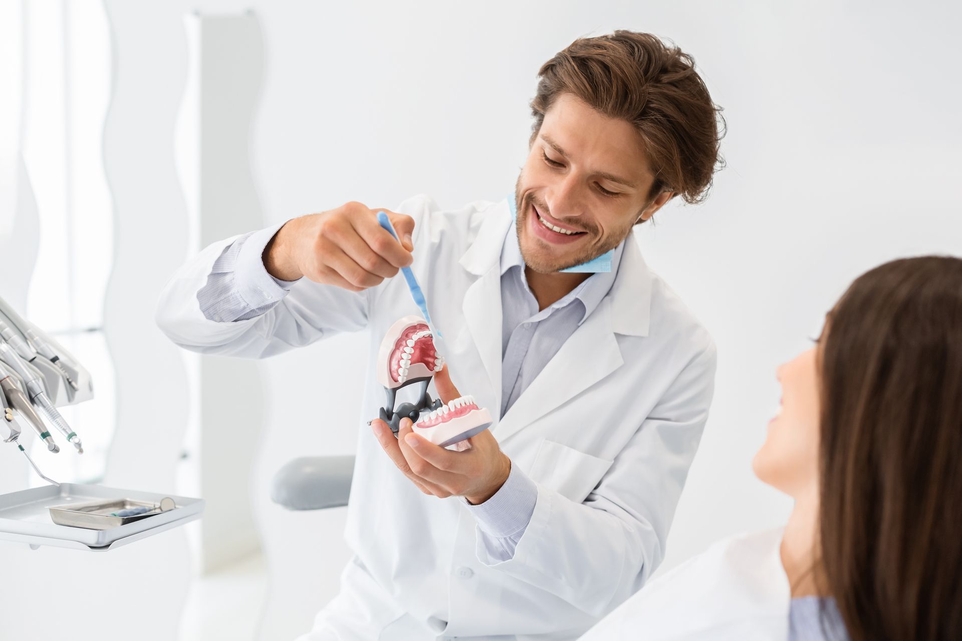 A dentist demonstrating toothbrushing technique with a dental model.