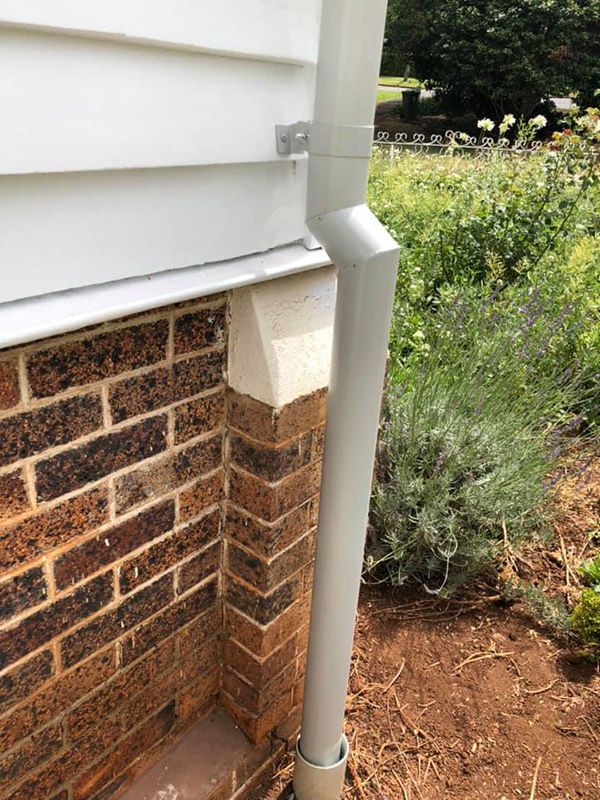 A Drainpipe Is Attached To The Side Of A Brick House — Gutters in Toowoomba, QLD