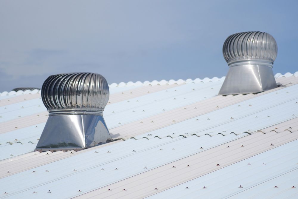 Two Stainless Steel Ventilators Are On The Roof Of A Building — Roofer in Toowoomba, QLD