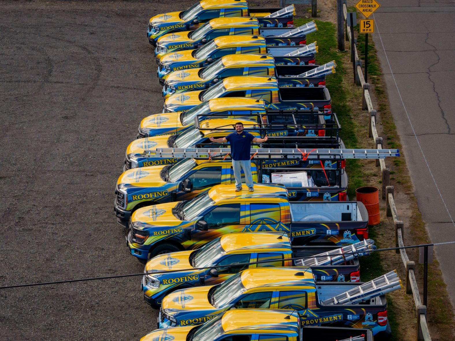 Rows of yellow-and-blue race cars lined up on a track, viewed from above, with one person standing between them