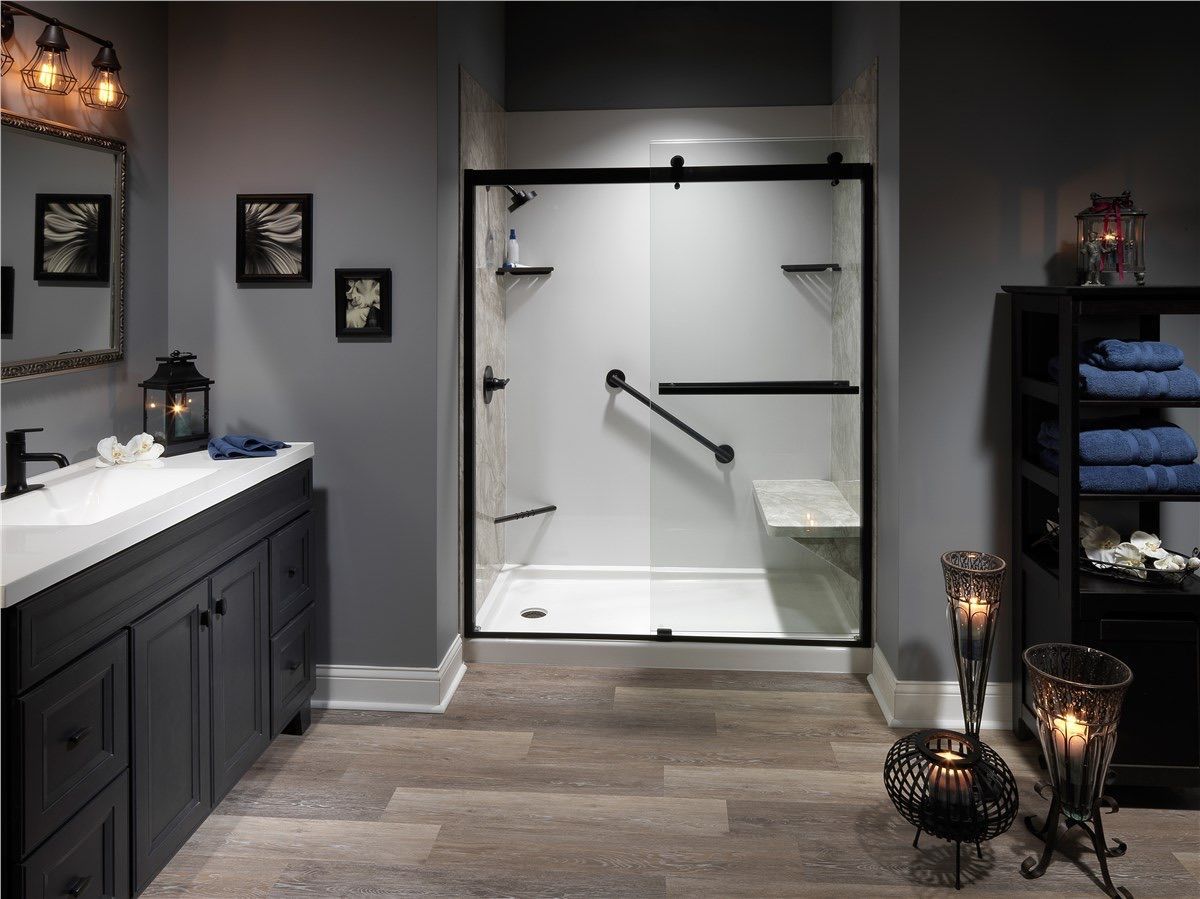 Modern bathroom with gray walls, a vanity with a white countertop, and a walk-in shower with a black frame and grab bar.