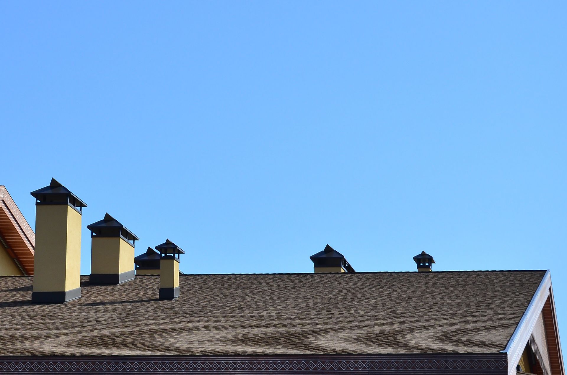 Rooftop with multiple chimneys against a clear blue sky