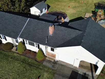 An aerial view of a large white house with a black roof.