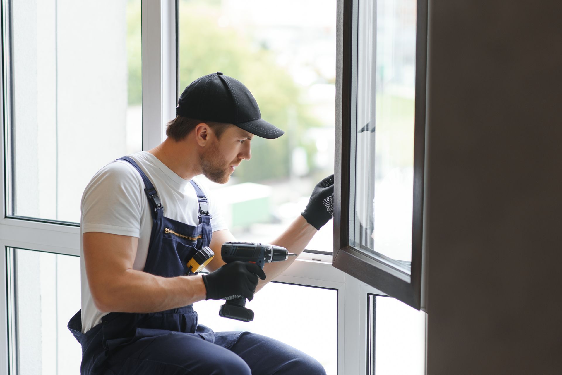 Person installing beige rain gutter under a building's overhang.