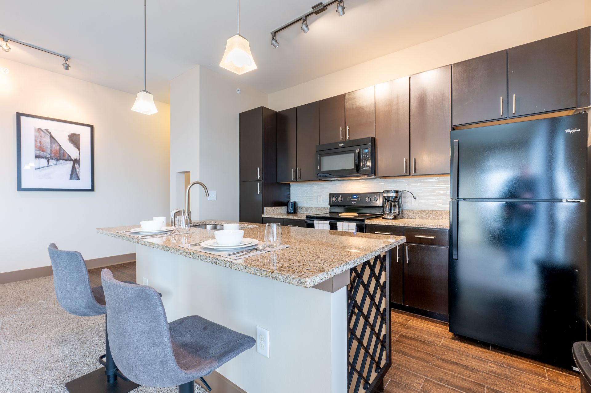 A kitchen with a black refrigerator , stove , microwave and sink.