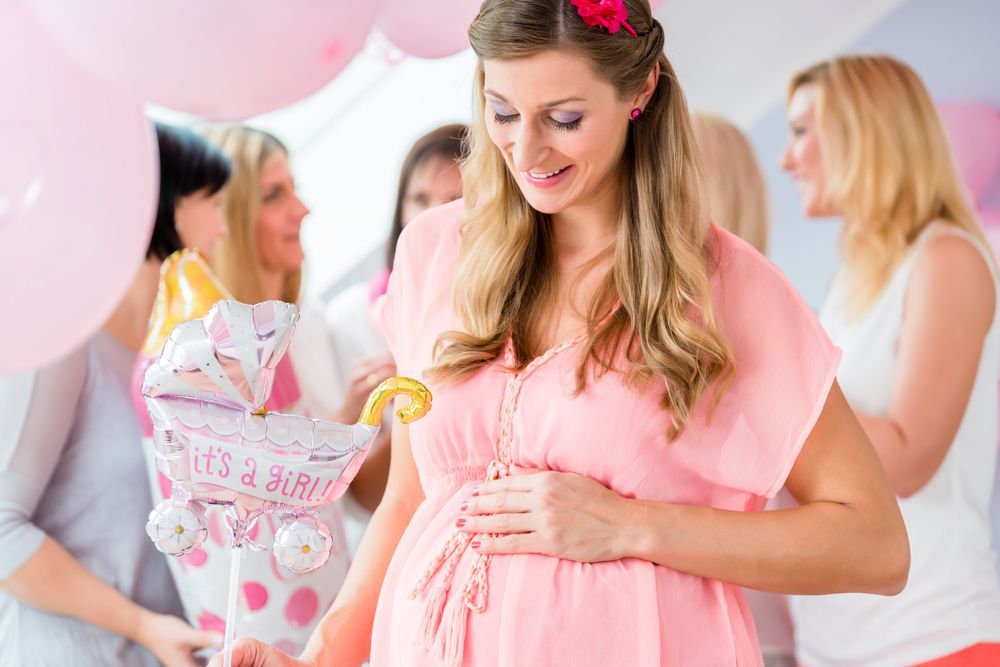 A pregnant woman is holding her belly at a baby shower.
