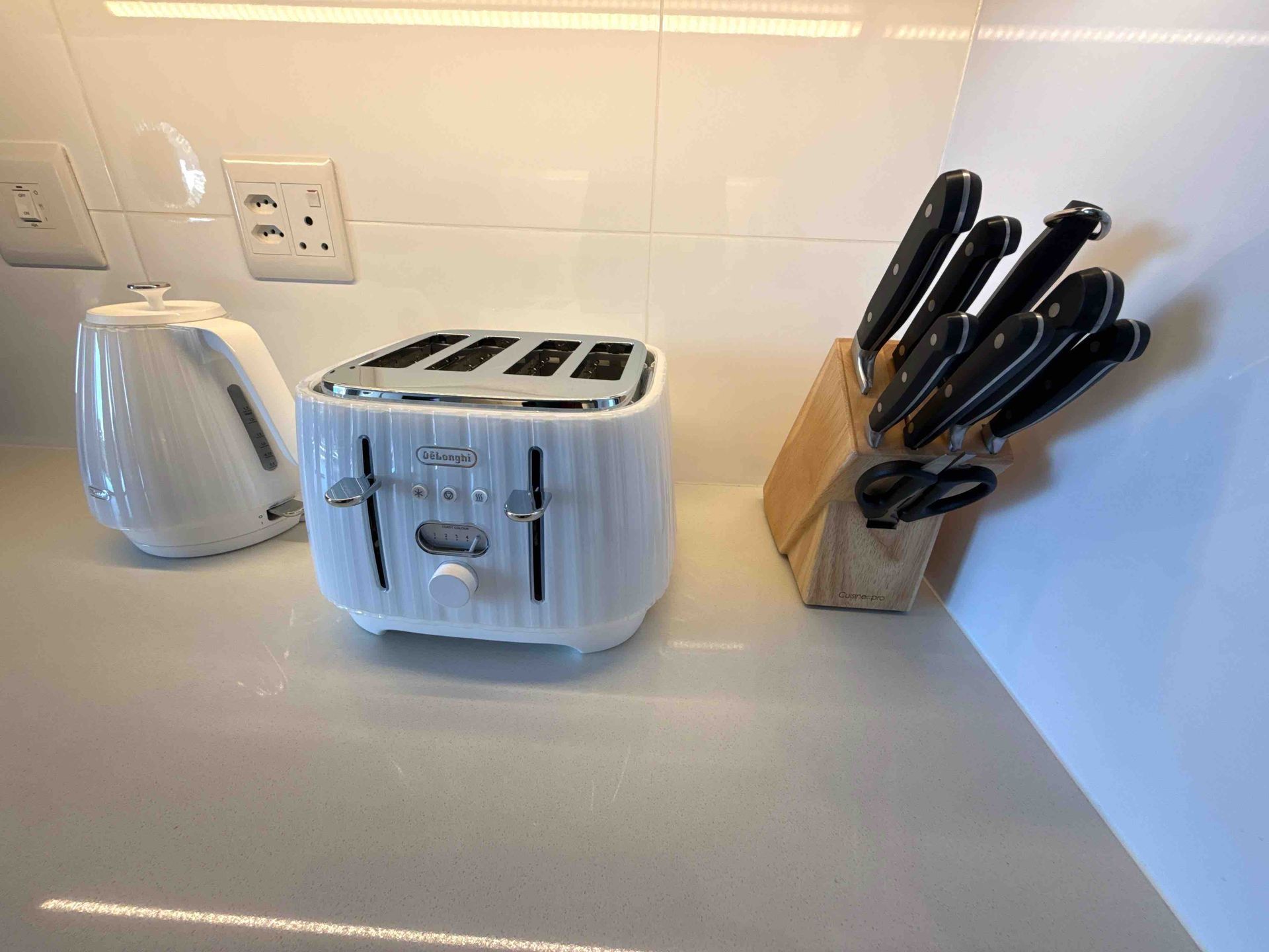 Kitchen counter with white toaster, electric kettle, and knife block against a tiled backsplash