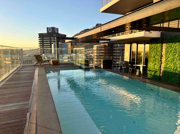 Rooftop infinity pool at sunset with city skyline and modern building