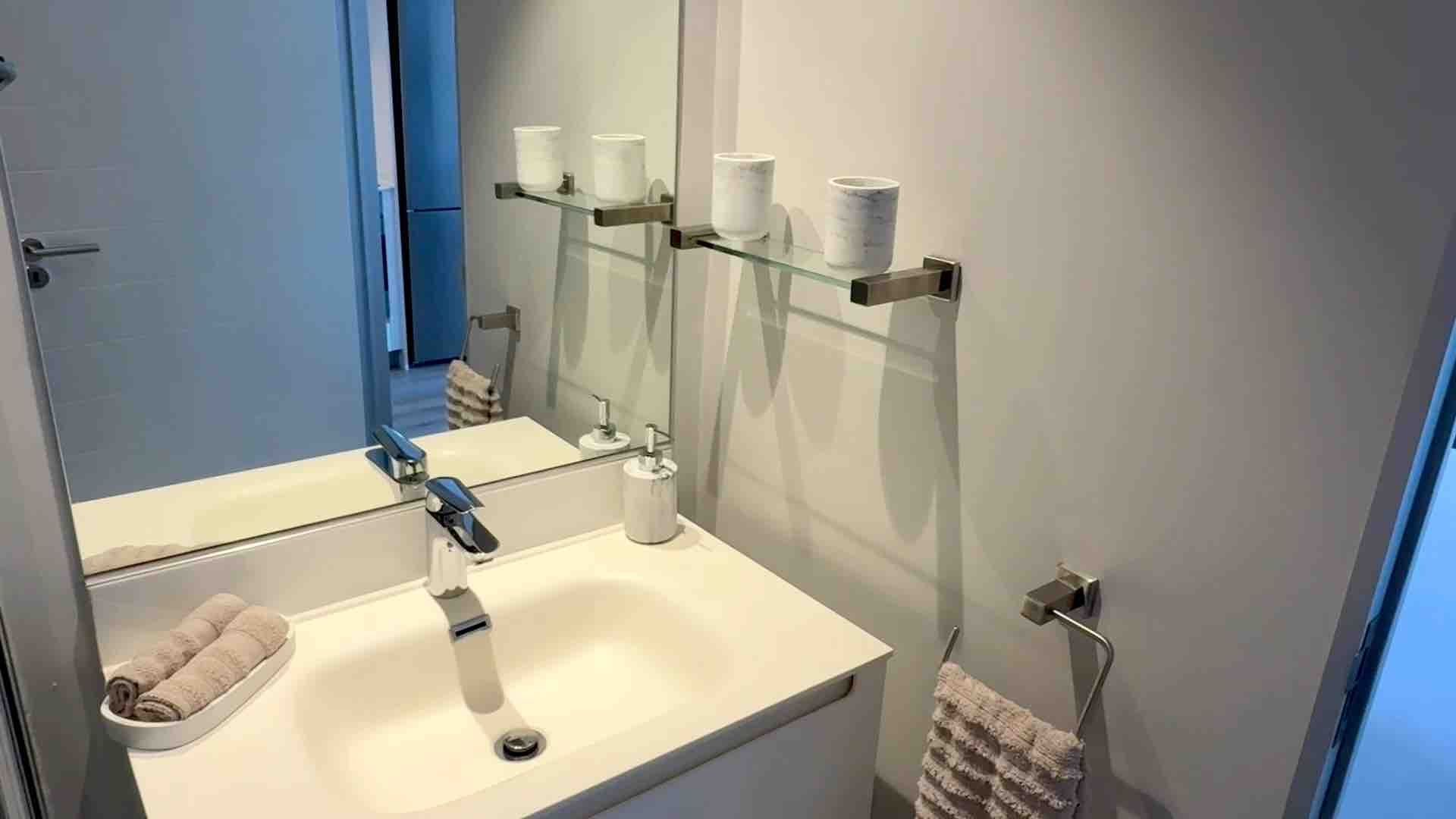 Bathroom sink with mirror, soap dispenser, candle holders, and neatly folded towels.