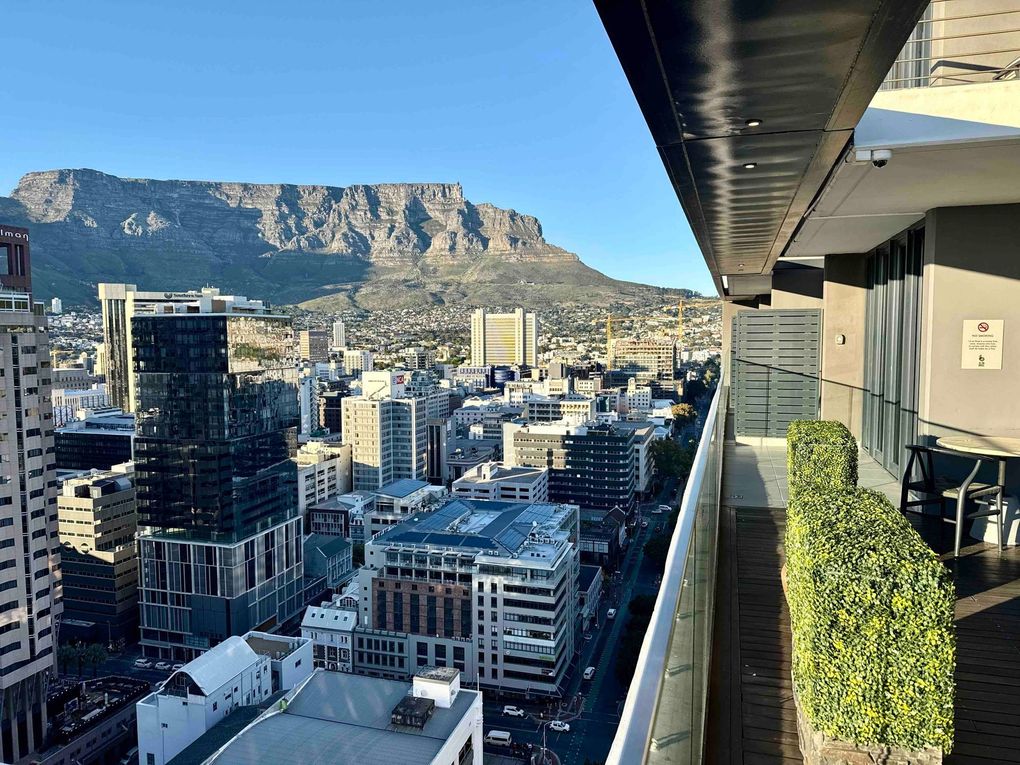 City skyline with Table Mountain in the background, viewed from a balcony with plants and outdoor seating.