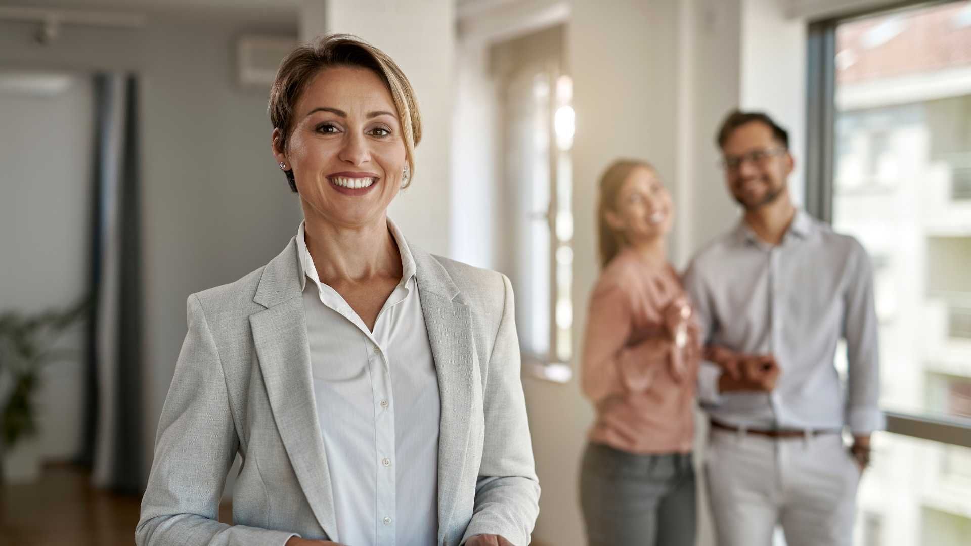 A woman is standing in front of a group of people in a room.