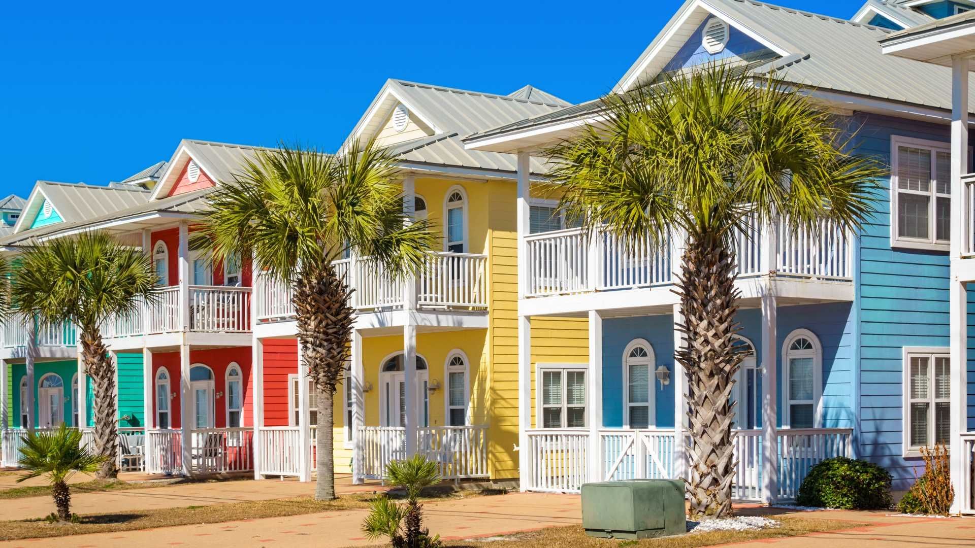 A row of colorful houses with palm trees in front of them.