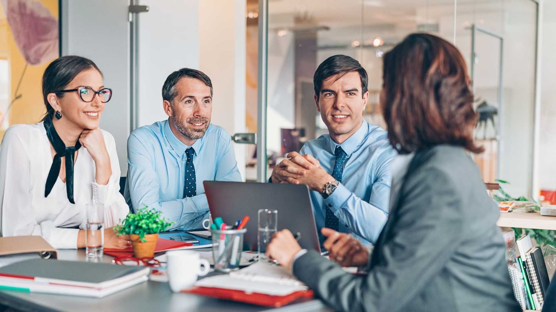 A group of people are sitting around a table having a meeting.