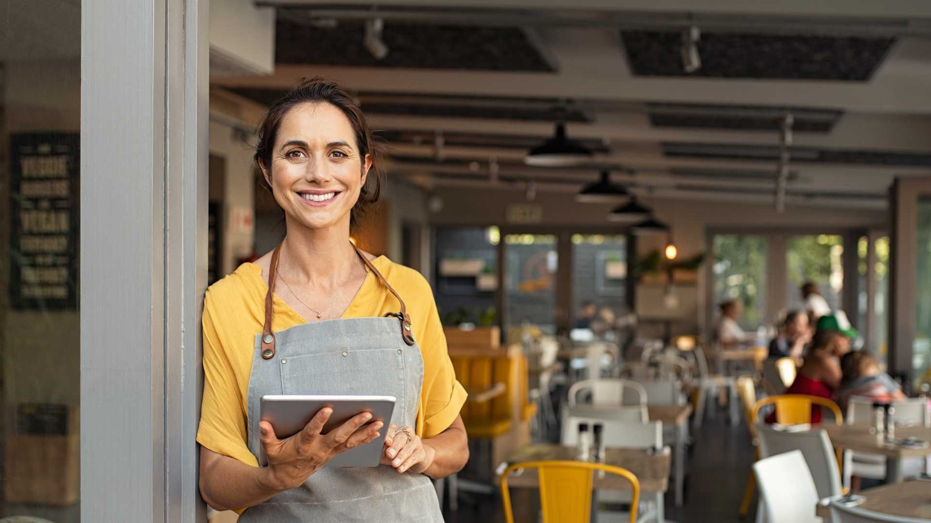 A woman is standing in a restaurant holding a tablet.