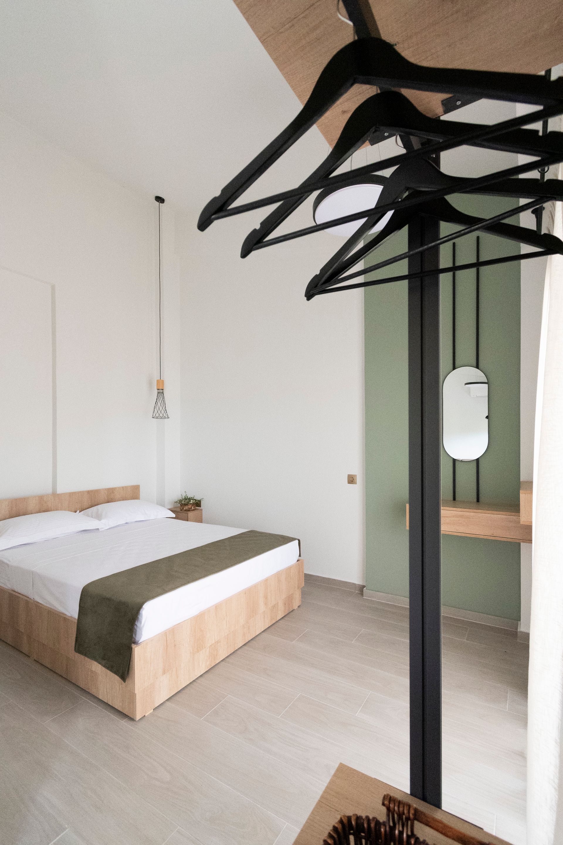 A bedroom with a bed and clothes hanging on the wall.