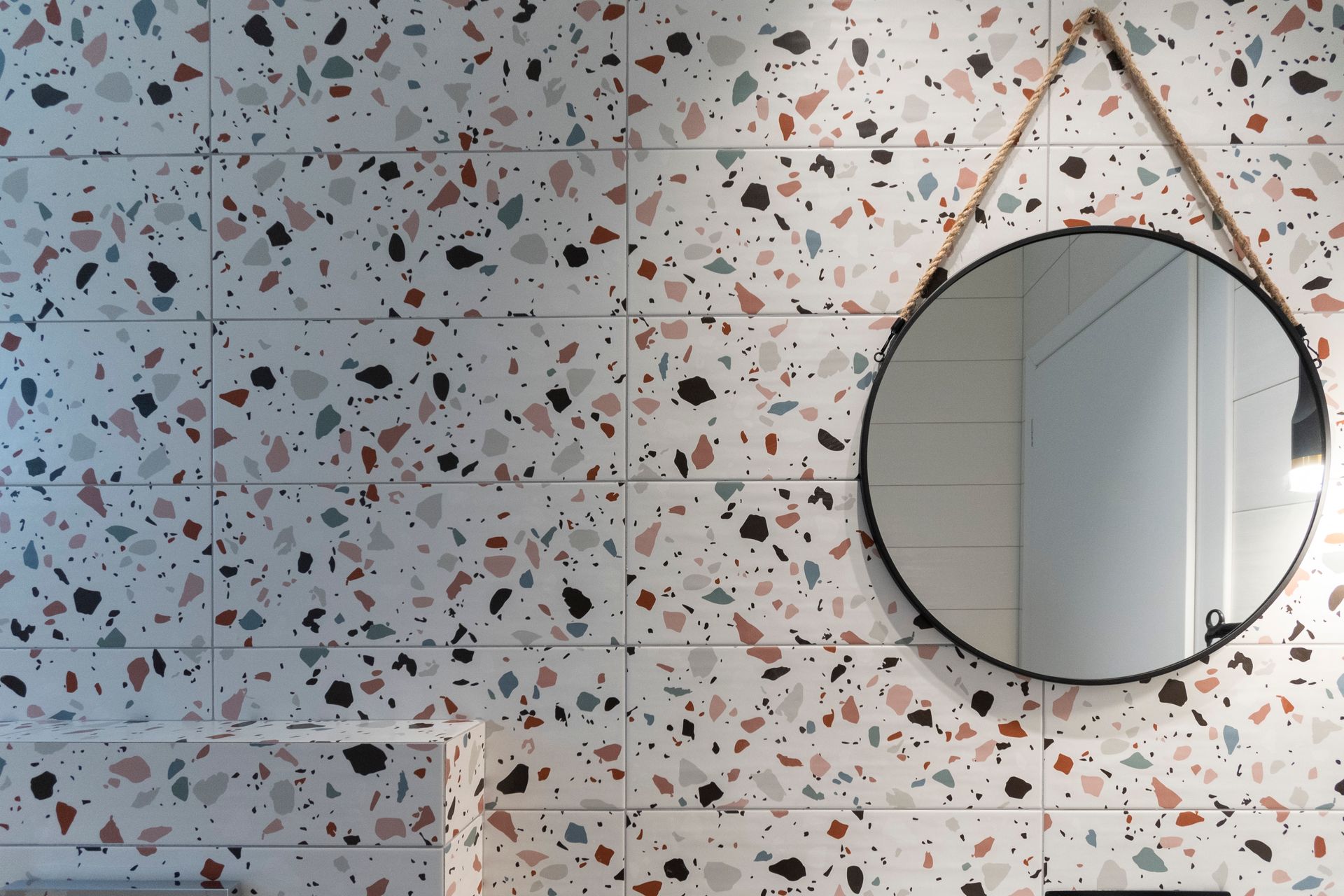 A bathroom with a round mirror hanging on the wall.
