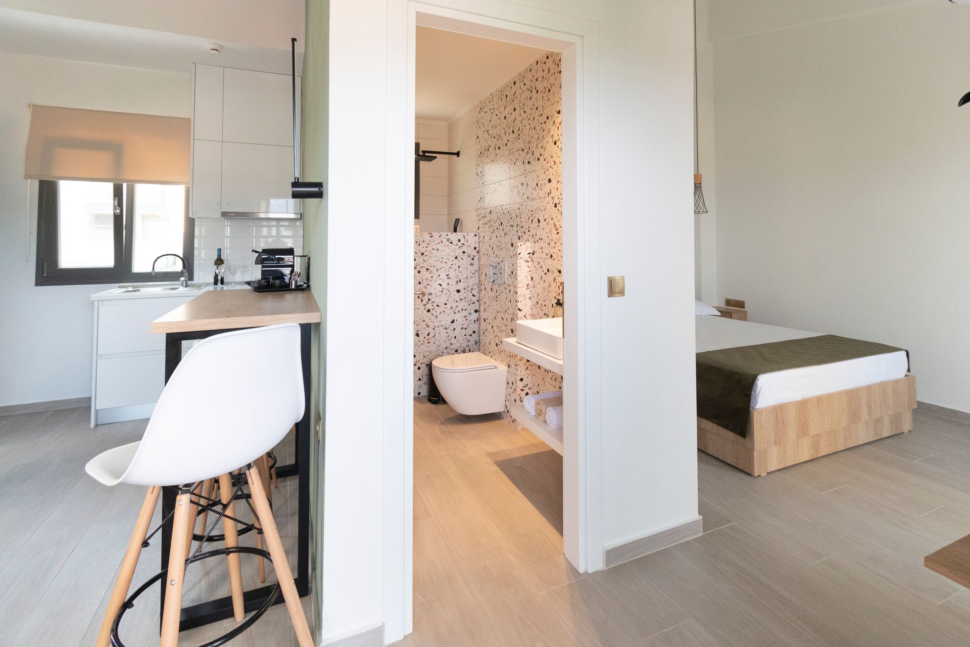 A bedroom with a bed , kitchen , and bathroom.