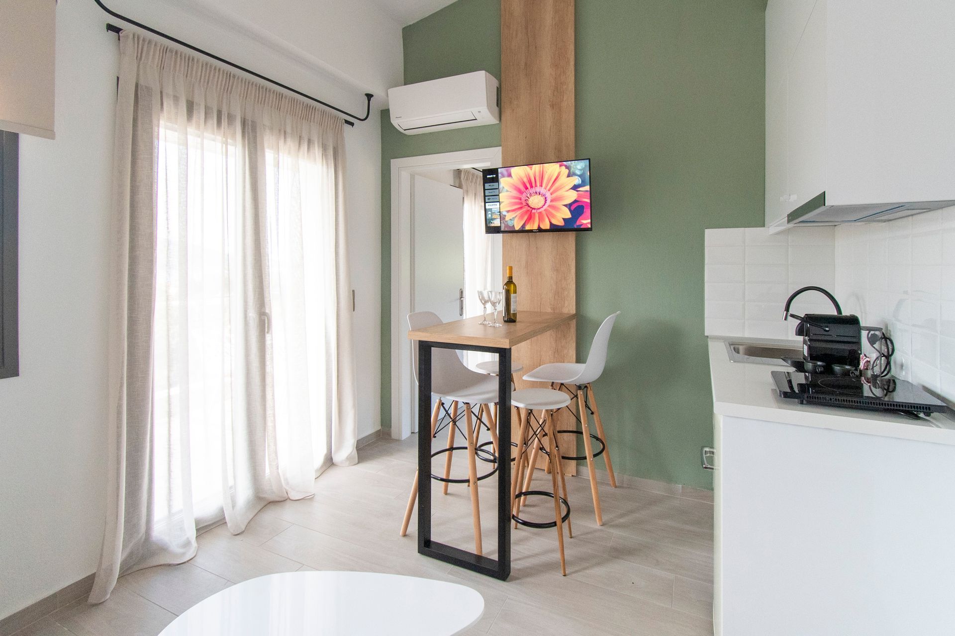 A living room with a table and chairs and a television on the wall.