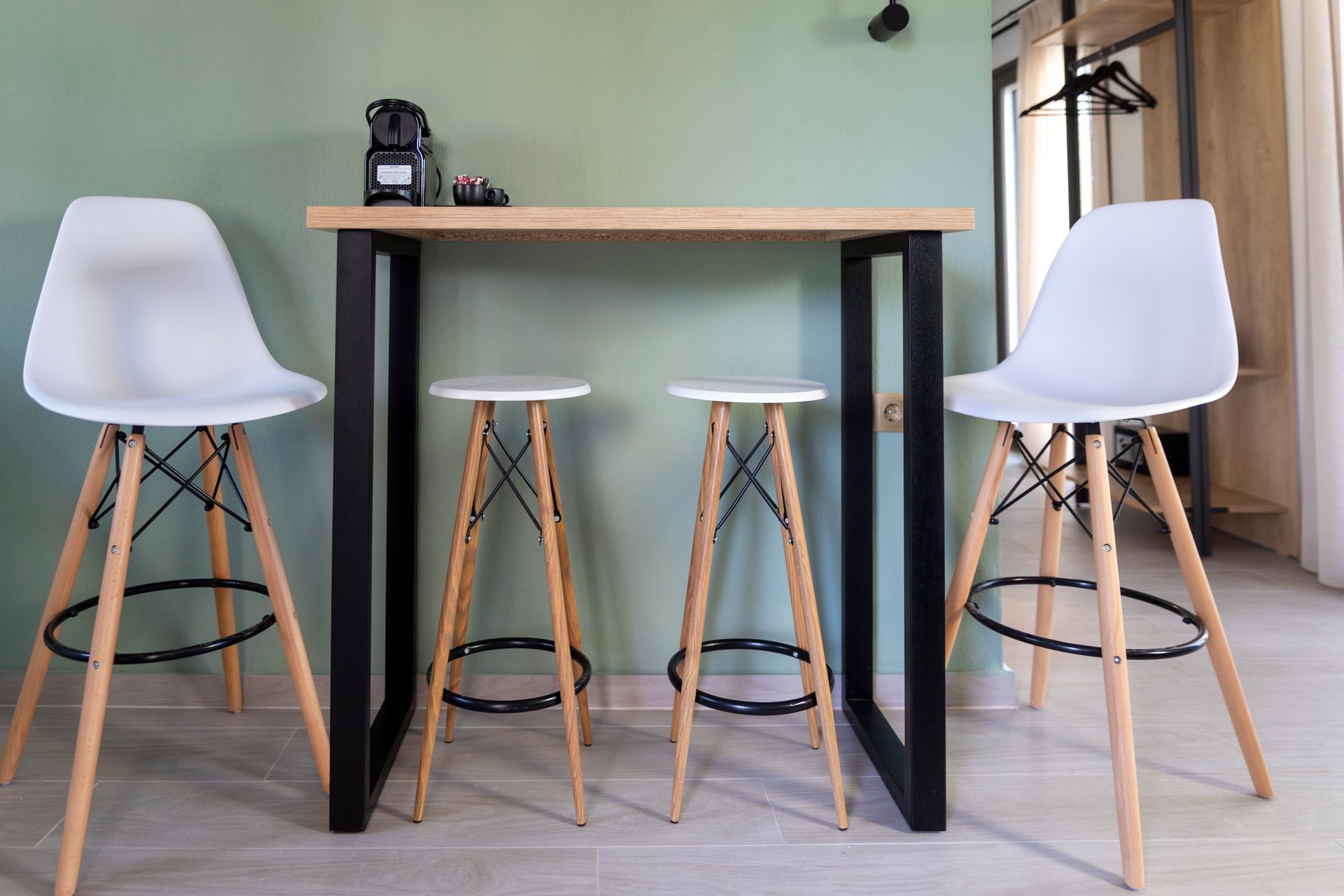 Three white bar stools are sitting next to a wooden table.