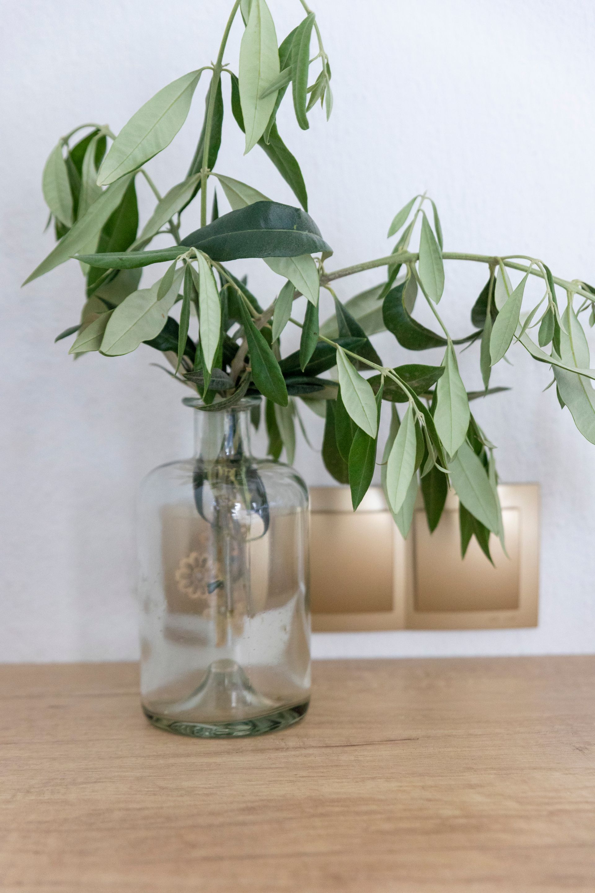 A vase filled with leaves is sitting on a wooden table.