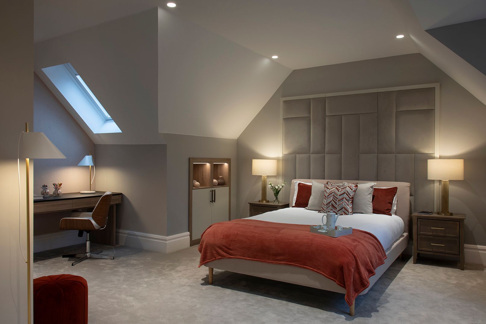 Sophisticated loft conversion bedroom with taupe panelled headboard, brass lighting, and terracotta velvet accents in Bushey