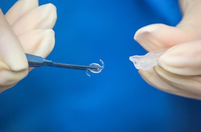 surgeon holding intraocular lens implant with tweezers