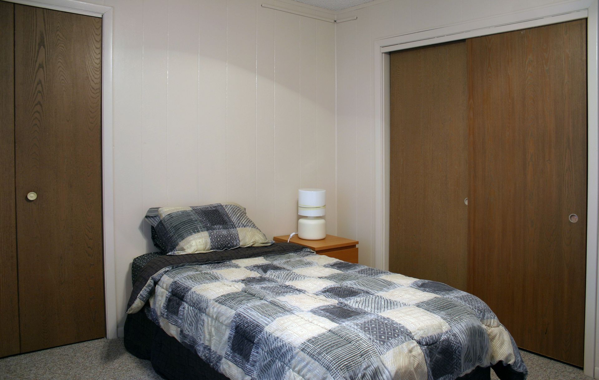 Photo showing a bed with a night stand and sliding dual-door closets