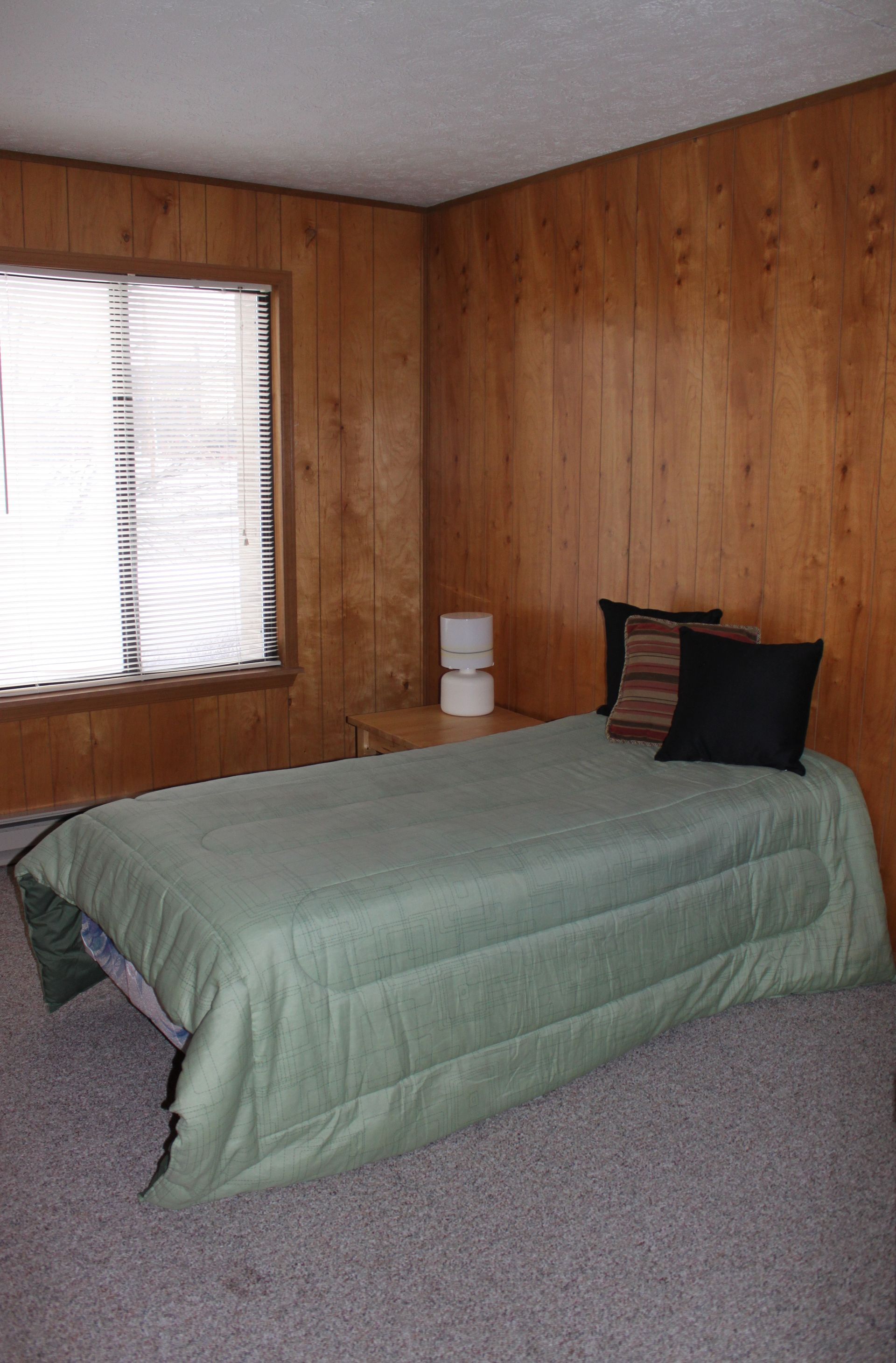 Photo showing a bed in a bedroom with a nightstand next to the bed