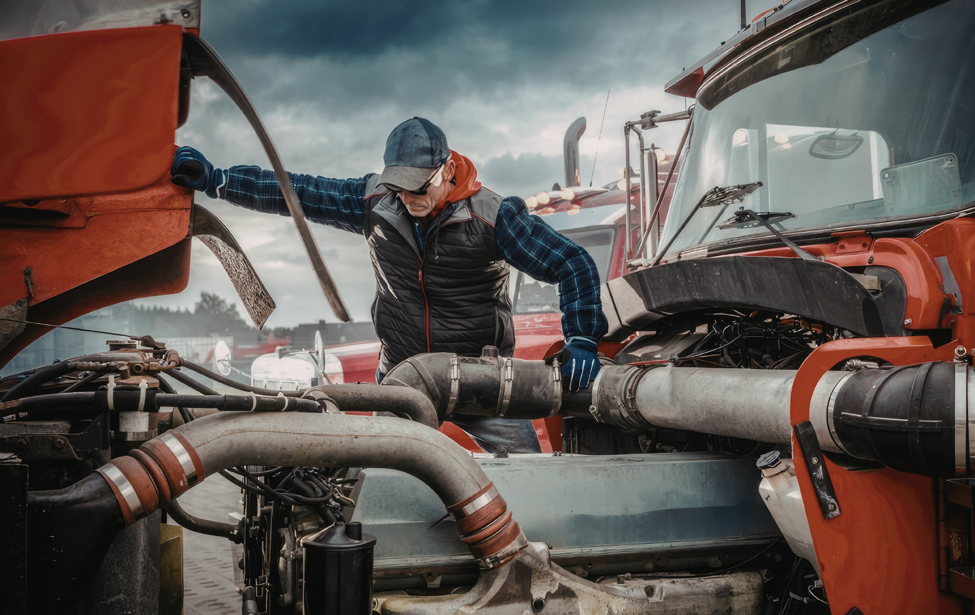 Worker in a blue jacket and beanie inspects red industrial pipes in a snowy facility