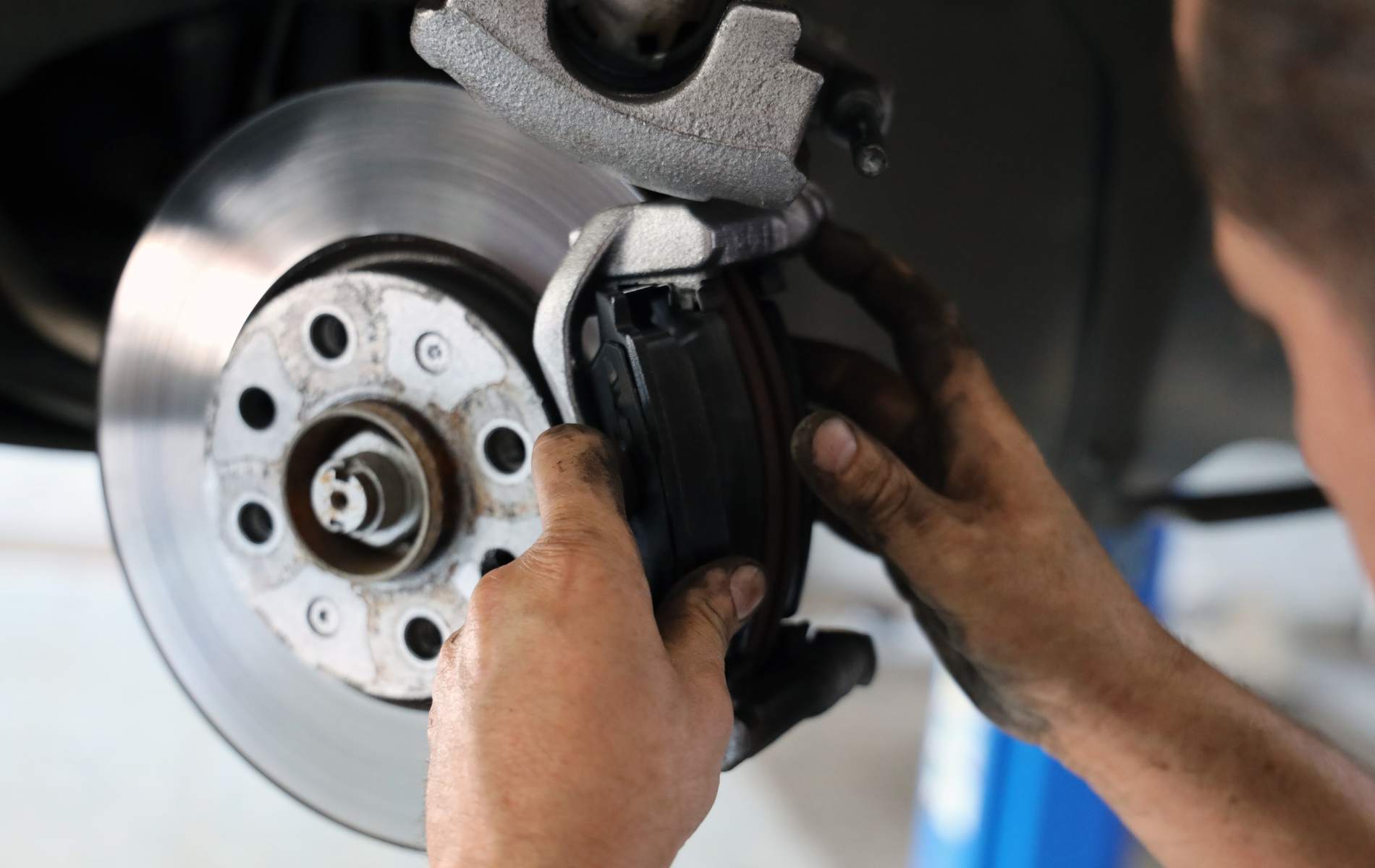 Mechanic installing a brake caliper on a car’s front disc brake assembly