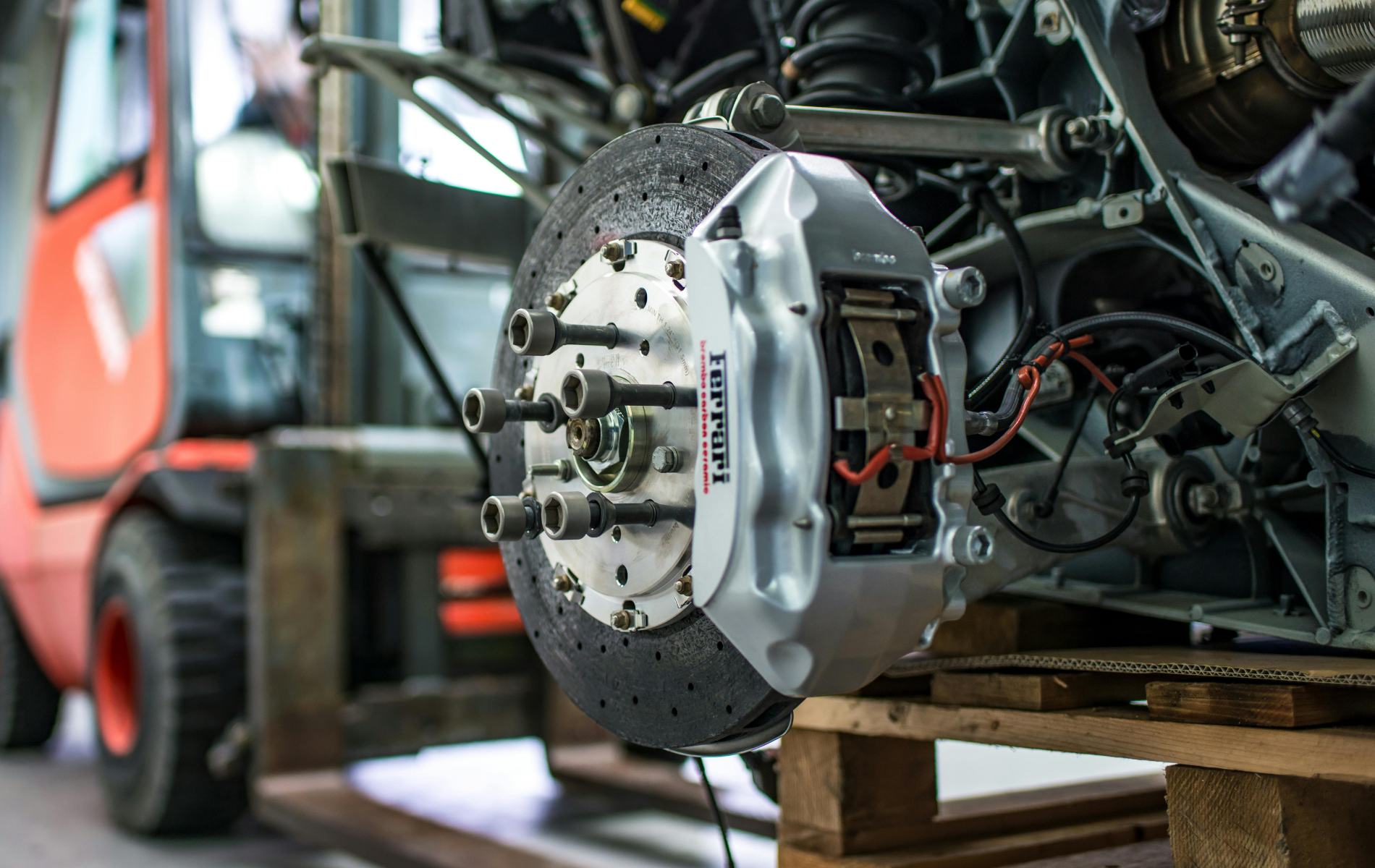Racing car with exposed brake assembly and suspension during mechanical repair in a workshop