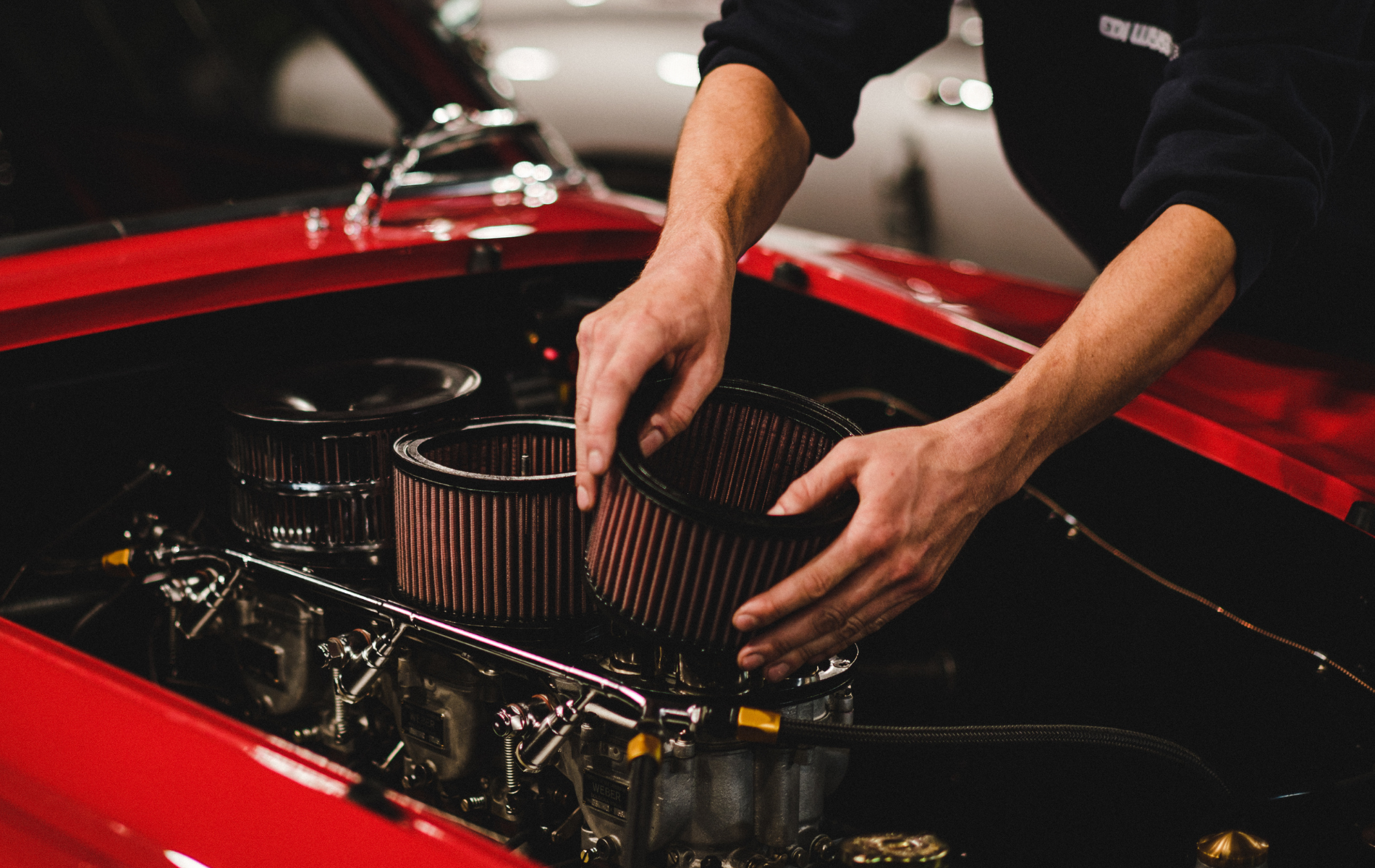 Mechanic installing air filters in a red car engine bay