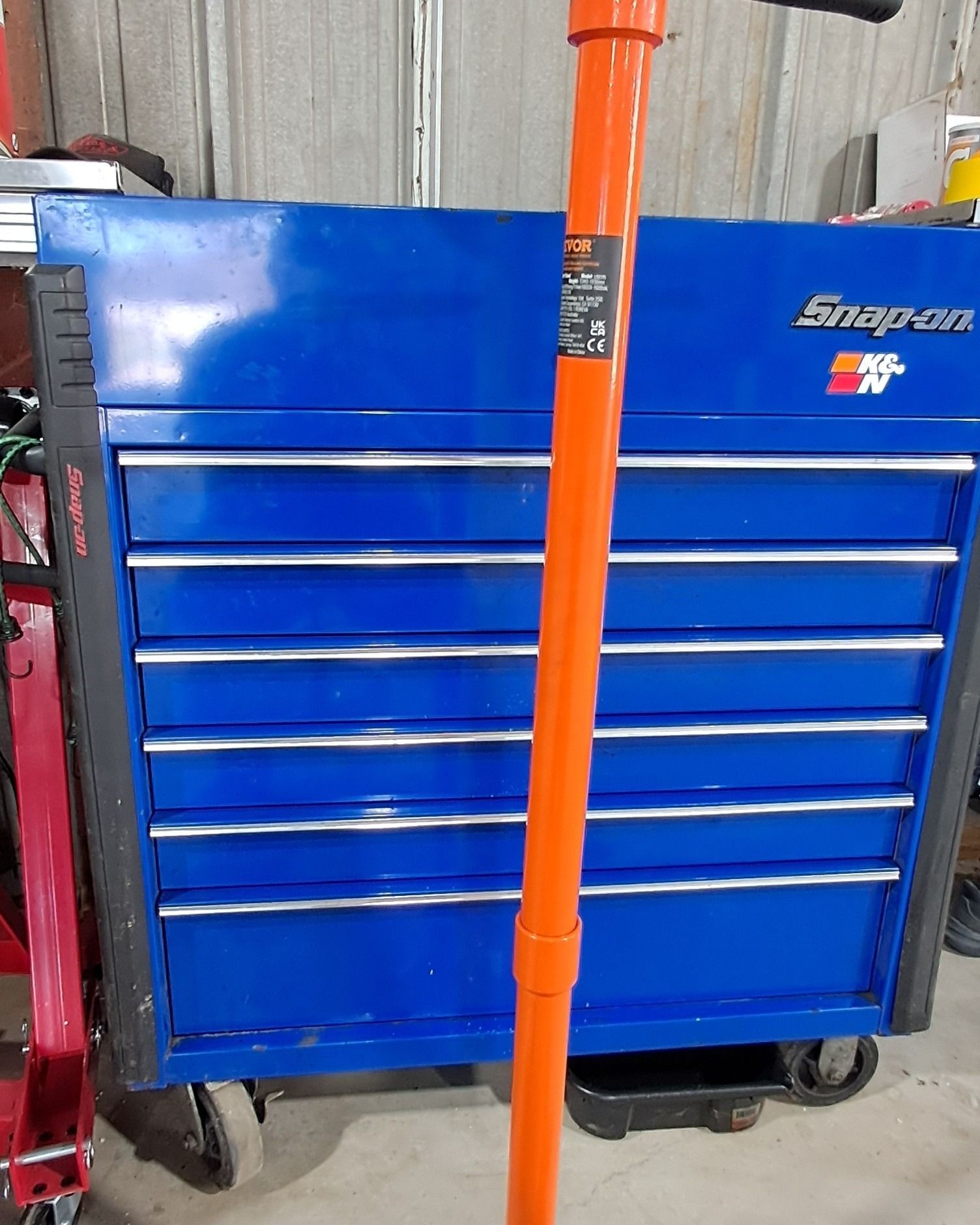 Blue Snap-on tool chest with orange handle in a workshop garage.