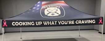 Banner reading “COOKING UP WHAT YOU’RE CRAVING” with pink ribbons on a table in a gray room