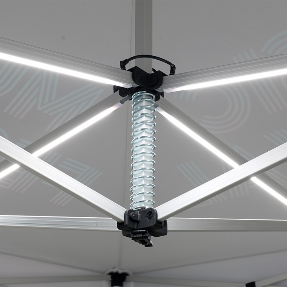 Close-up of a white canopy tent frame with a central spring-loaded connector and LED strip lights behind it