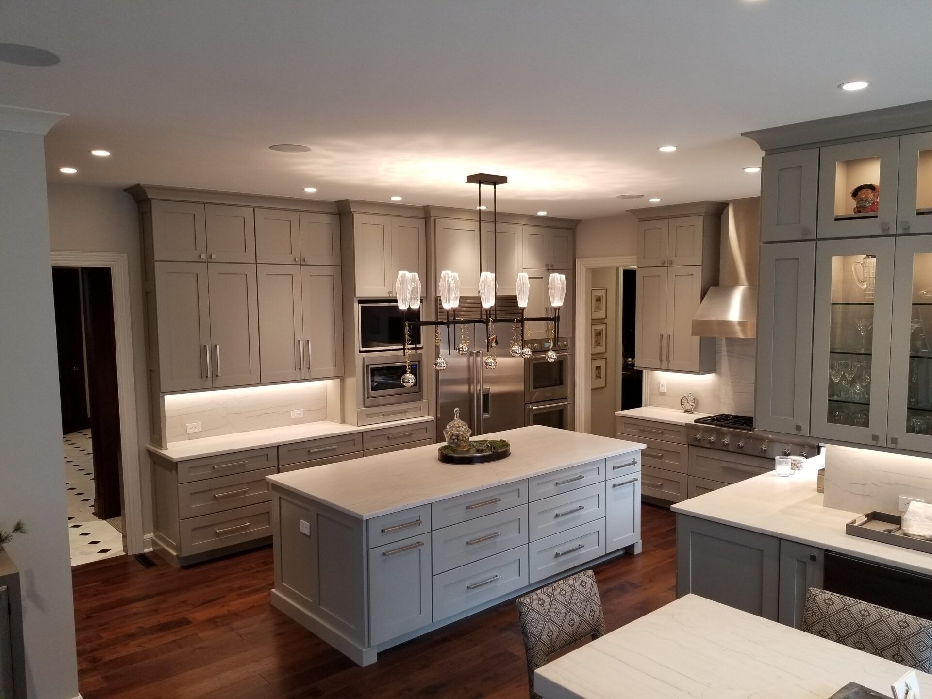 Spacious kitchen with gray cabinets, white countertops, large island, and hardwood floors.