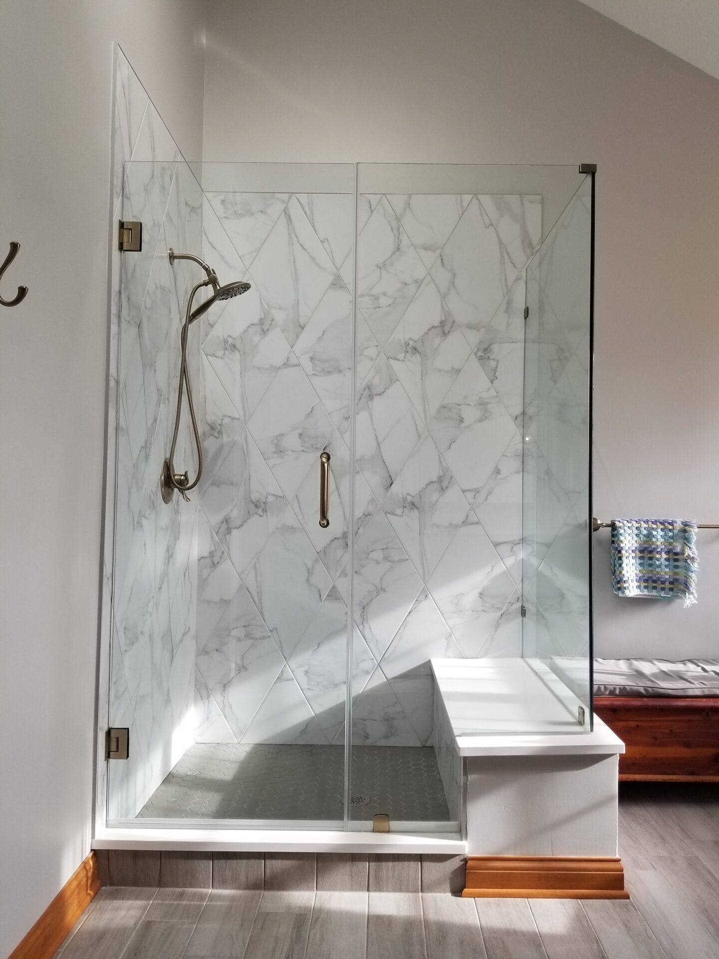 Glass shower enclosure with white marble tile and bronze fixtures.