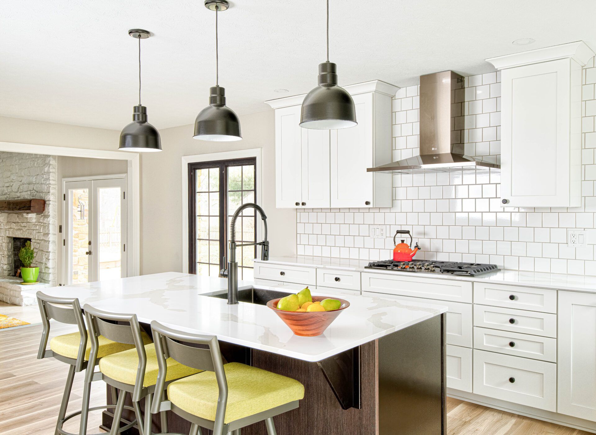 Modern kitchen with white cabinets, island with stools, and black pendant lights.