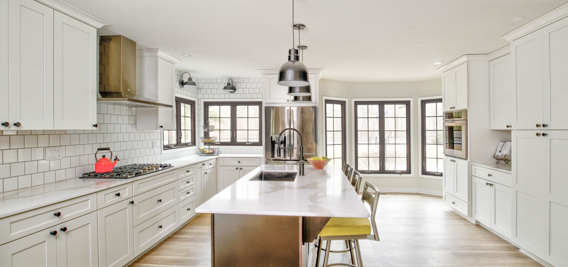 Modern white kitchen with island, stainless steel appliances, and wood flooring.