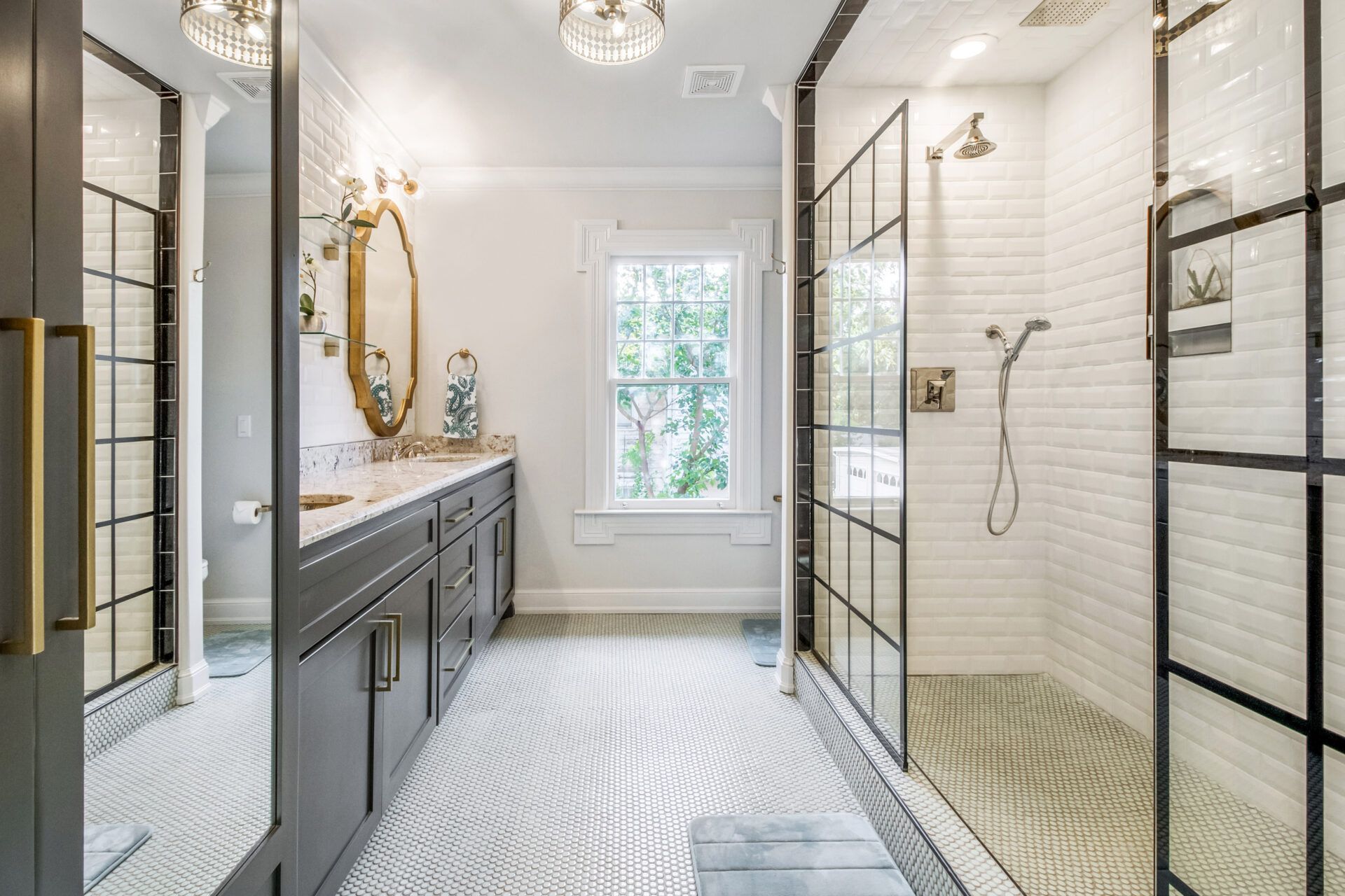 Bathroom with gray cabinetry, white tile, a glass-enclosed shower, and decorative gold accents.