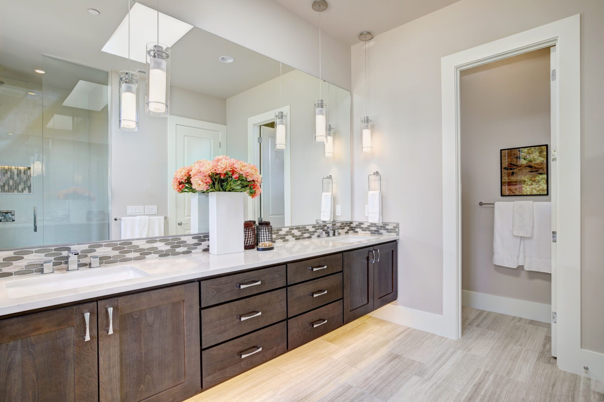 Bathroom with dark wood vanity, large mirror, and open doorway to a toilet room.