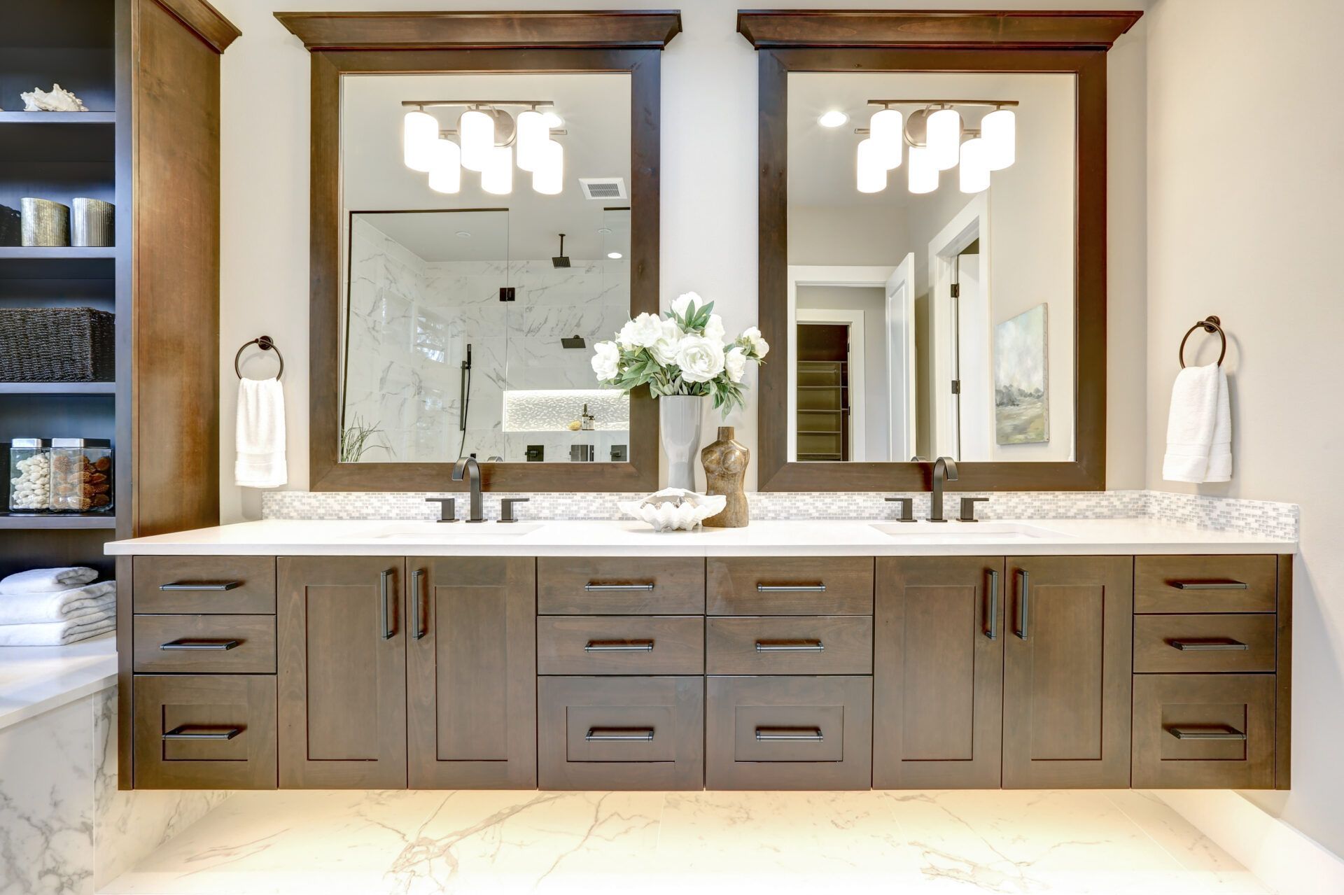 Bathroom with double sinks, two mirrors, brown cabinets, and white countertop.