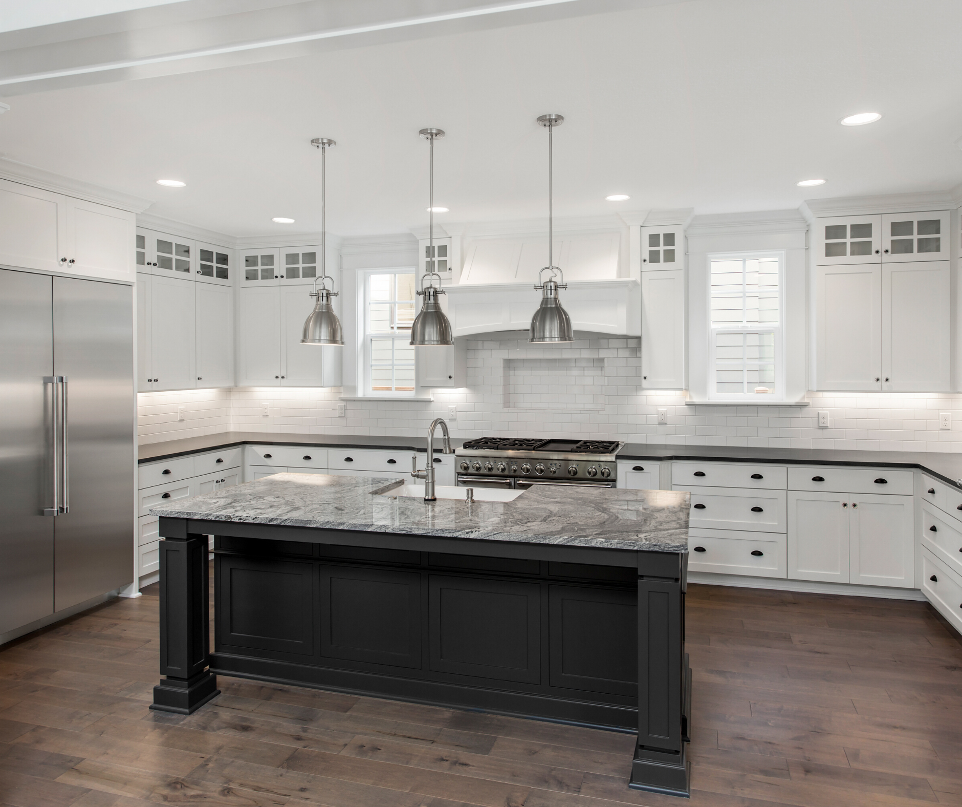 White kitchen with dark island and stainless steel appliances.