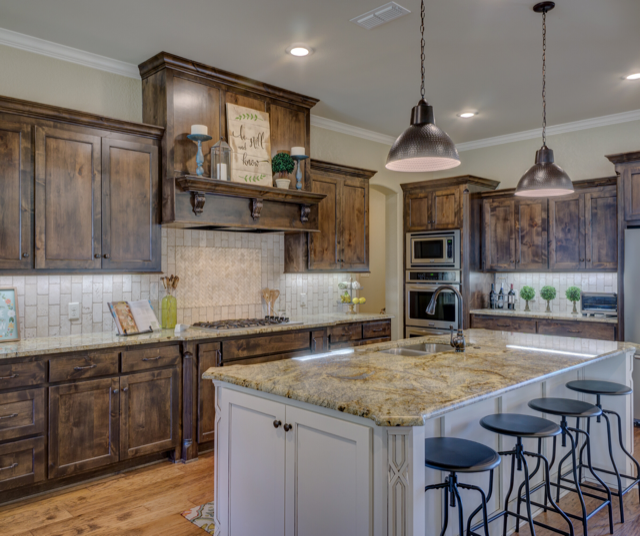 Kitchen with dark wood cabinets, light countertops, and an island with bar stools.