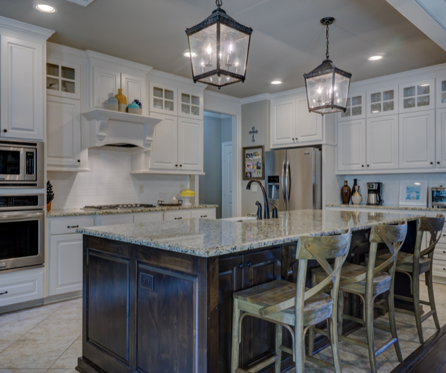 White kitchen with dark wood island, granite counters, stainless steel appliances, and lantern light fixtures.
