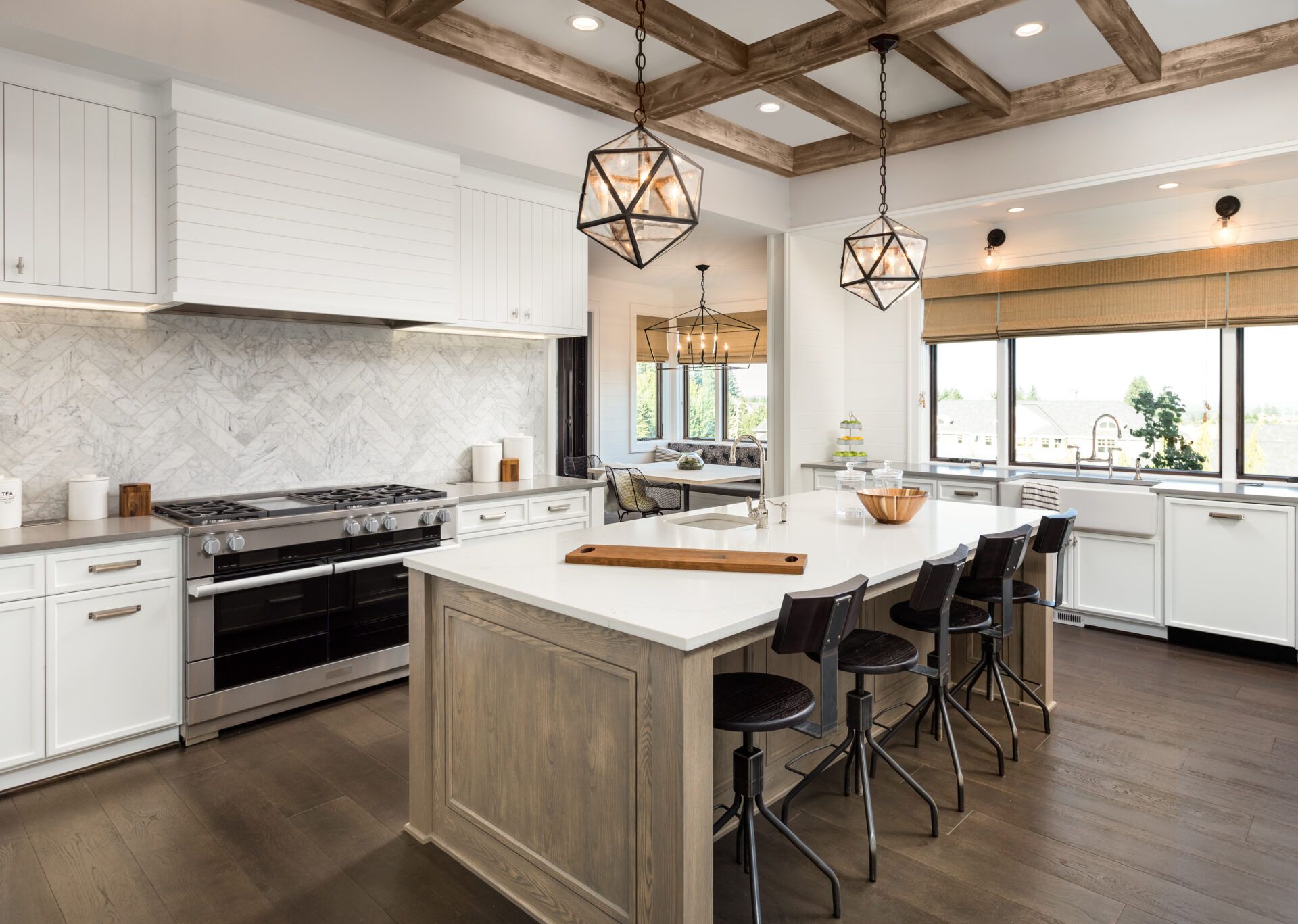 Modern kitchen with large island, stainless steel appliances, and wood-beam ceiling.